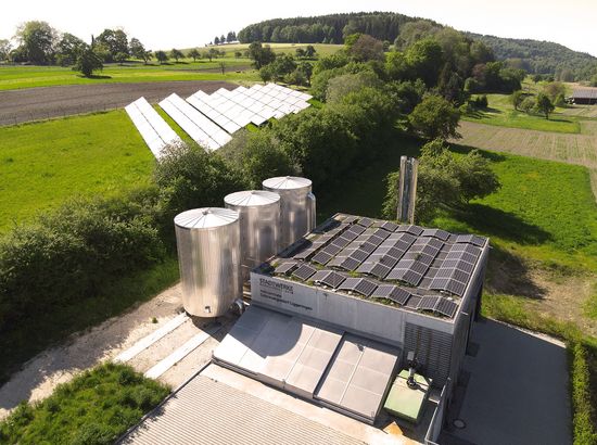 Solarenergieanlage mit großen Solarkollektoren und Wärmespeichern in ländlicher Umgebung.