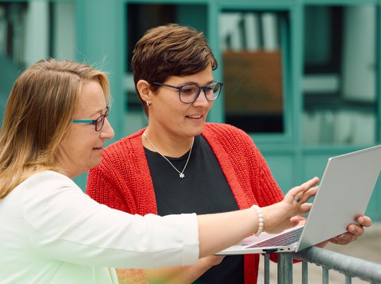 Zwei Personen besprechen gemeinsam Inhalte auf einem Laptop, beide schauen konzentriert auf den Bildschirm.