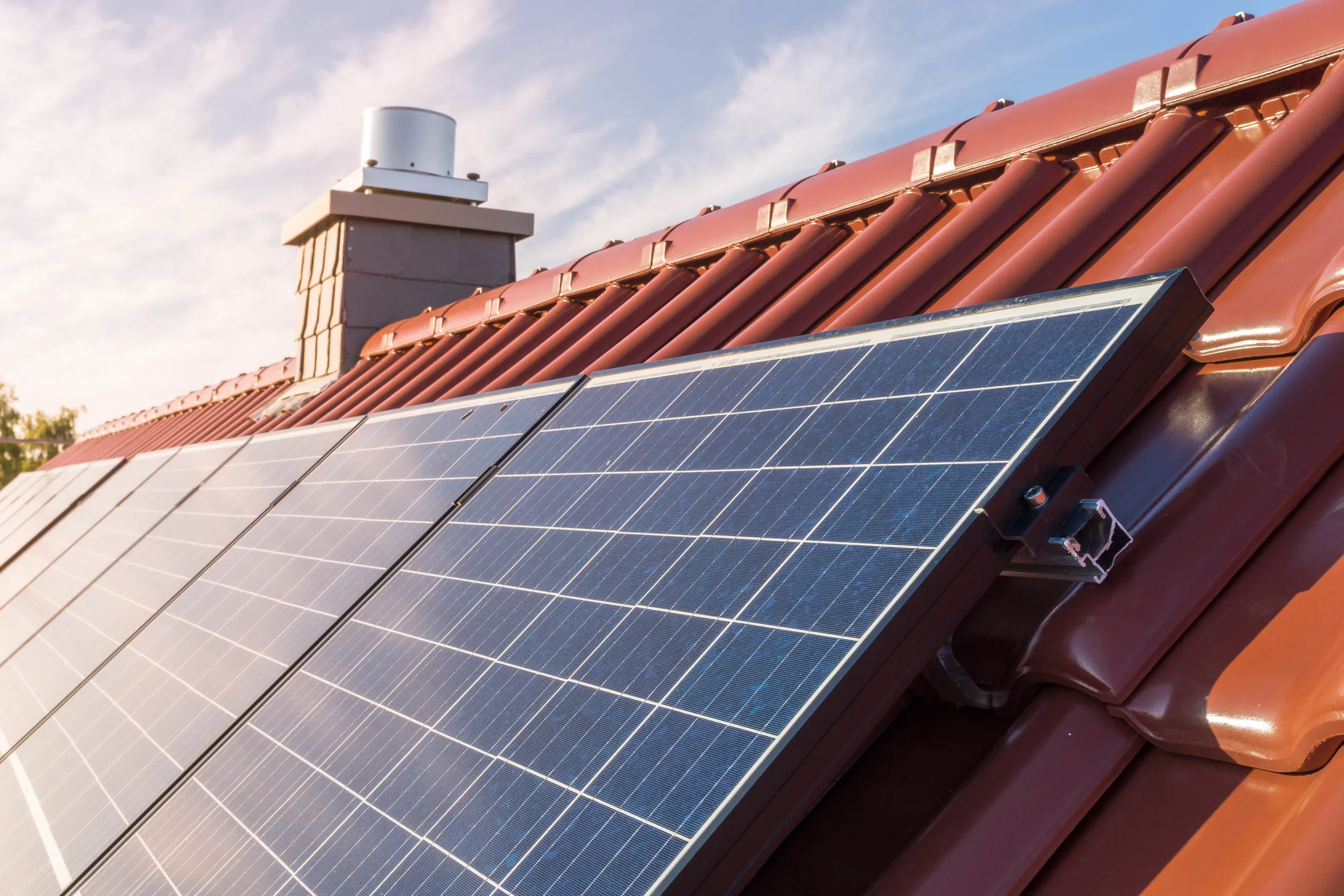 Solarpanels auf einem Dach mit roten Ziegeln, die zur Stromerzeugung durch Sonnenenergie genutzt werden.
