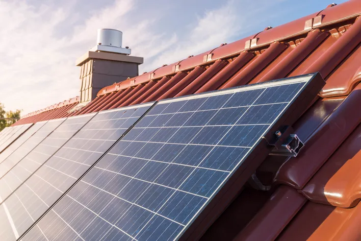 Solarpanels auf einem Dach mit roten Ziegeln, die zur Stromerzeugung durch Sonnenenergie genutzt werden.