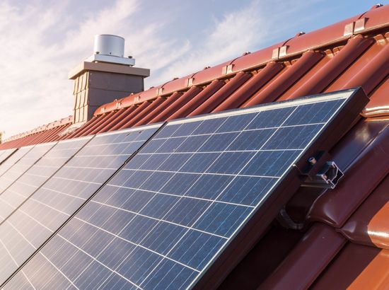 Solarpanels auf einem Dach mit roten Ziegeln, die zur Stromerzeugung durch Sonnenenergie genutzt werden.
