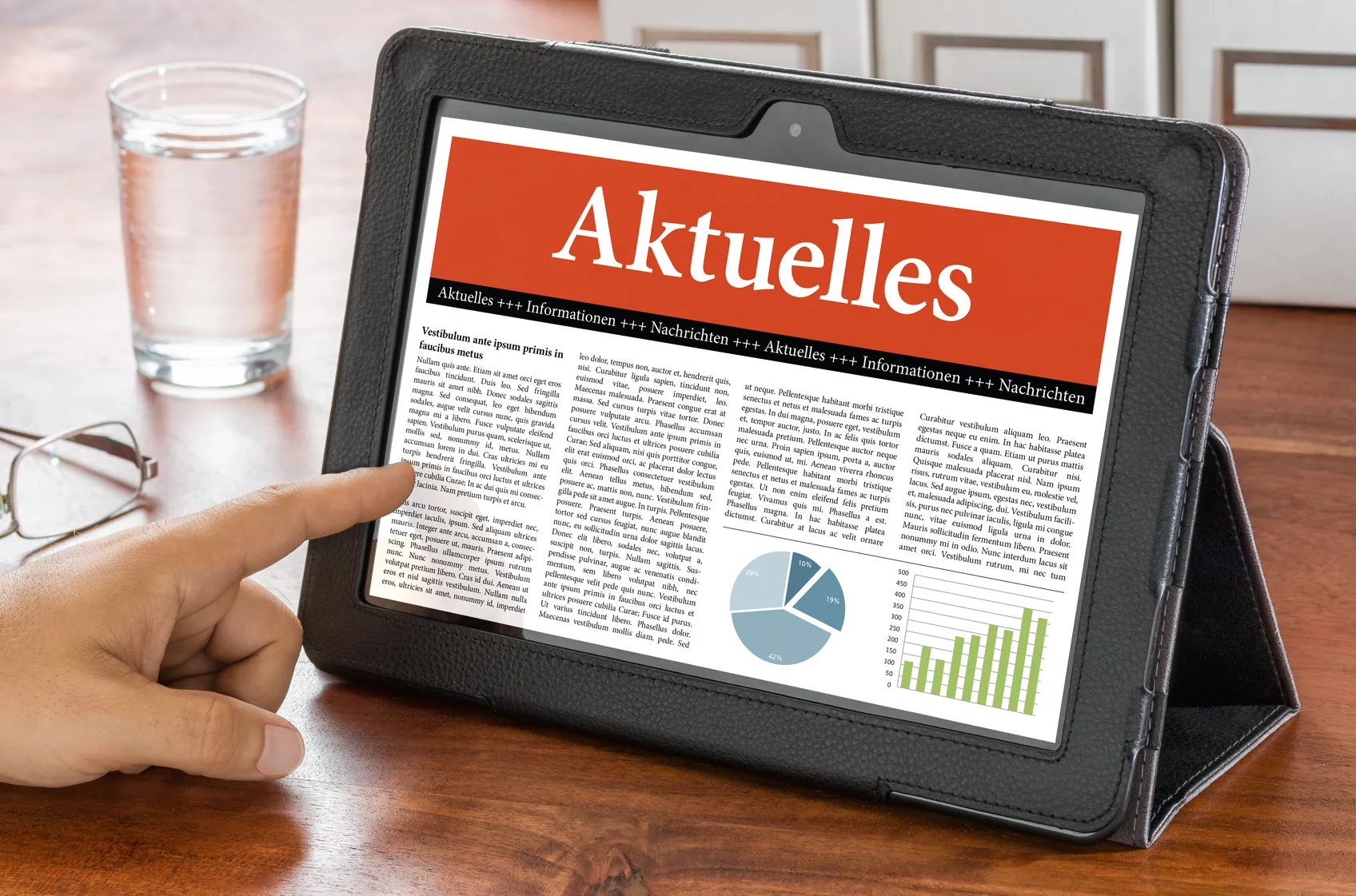 Person nutzt Tablet mit einer Nachrichtenwebsite namens Aktuelles und zeigt auf den Bildschirm.