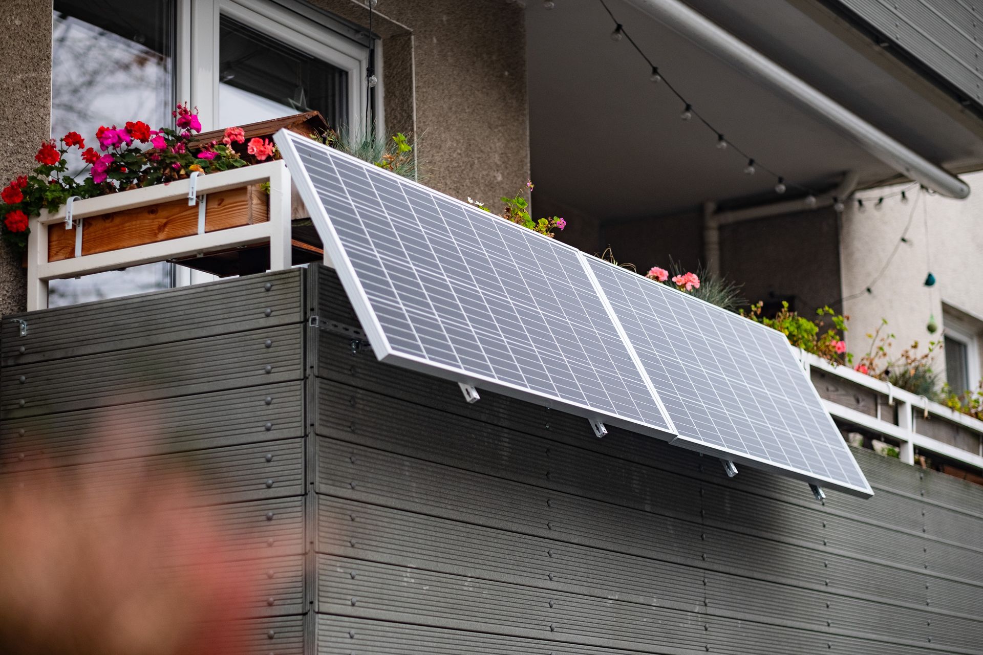 Solarpanel auf einem geneigten Balkon mit Blumenkübel im Hintergrund.