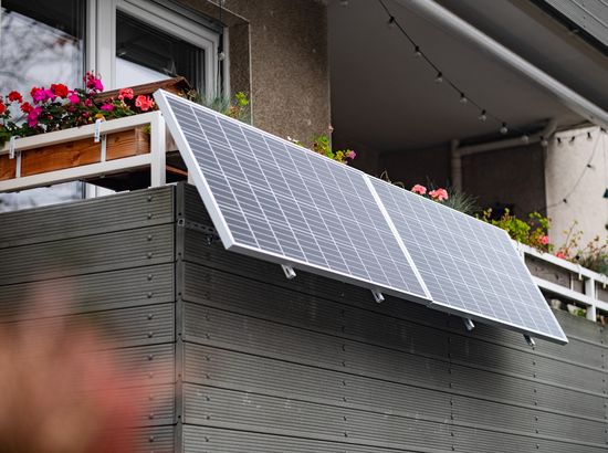 Solarpanel auf einem geneigten Balkon mit Blumenkübel im Hintergrund.