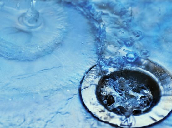 Wasser fließt in einen Abfluss und bildet Wirbel.