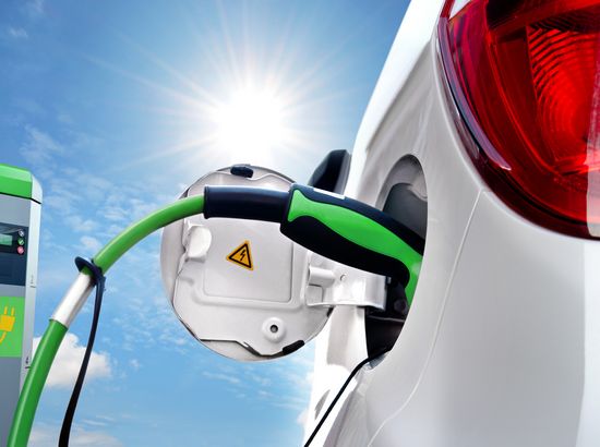 Ein Elektroauto wird an einer Ladestation mit grünem Kabel angeschlossen.