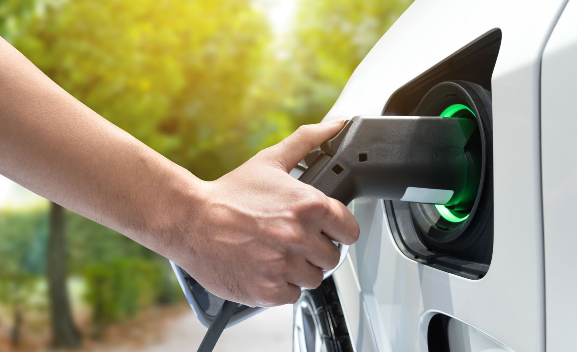 Eine Person steckt ein Ladekabel in die Ladebuchse eines Elektrofahrzeugs zum Aufladen der Batterie.