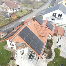 Hausdach mit Solaranlage aus mehreren Photovoltaikmodulen in einer Wohnsiedlung.
