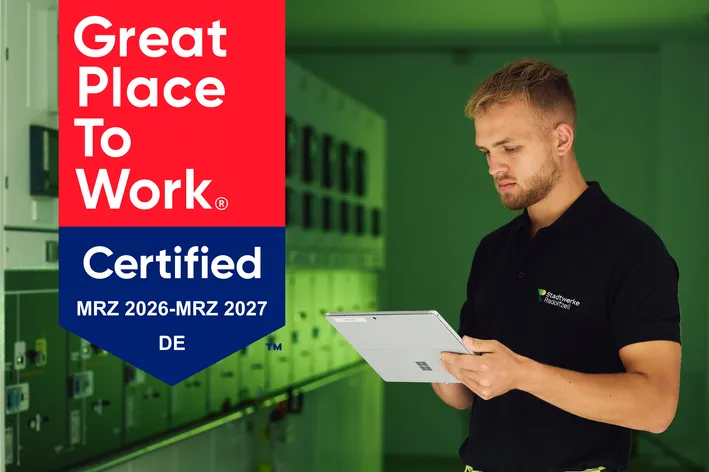 Ein Mitarbeiter mit Tablet in einem Büroumfeld, der eine Great Place to Work Zertifizierung für MRZ 2026 bis MRZ 2027 in Deutschland zeigt.