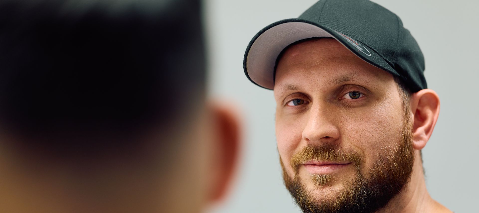 Nahaufnahme von einem Mann Anfang 30. Er lächelt und schaut direkt in die Kamera.