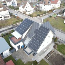Hausdach mit Solaranlage aus zahlreichen Photovoltaikmodulen in einer Wohnsiedlung.