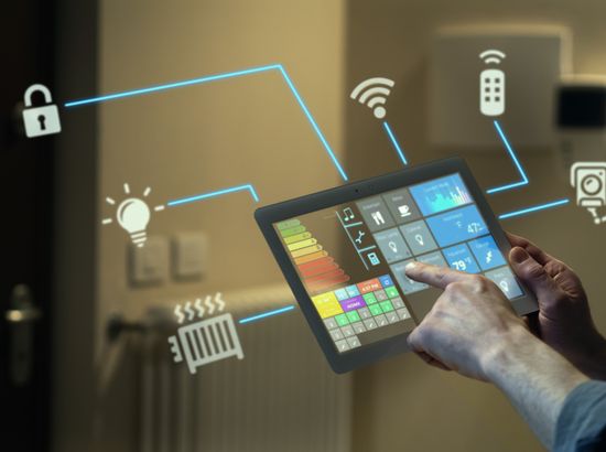 Eine Person bedient ein Smart Home Tableau zur Steuerung von Hausgeräten und Energieverbrauch, verbunden mit verschiedenen vernetzten Funktionen wie Beleuchtung, Heizung und Sicherheitssystemen.