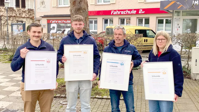 Vier Personen halten Urkunden für den TOP Lokaleinkaufsvergleiche 2020 vor einer Fahrschule.